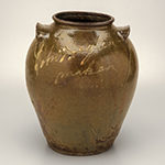 Fig. 13: Alkaline-glazed storage jar with kaolin slip decoration by John W. Seigler, 1854, Edgefield District, SC. Decorated in kaolin slip: "John Seigler/maker.” HOA: 14-5/8″; WOA: 12″. MESDA, William C. and Susan S. Mariner Collection, Acc. 5813.50.