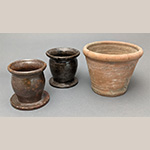 Fig. 29 Flowerpots by William F. James, Farmington, Davie County, NC; ca. 1900-1939. Earthenware, the smaller examples are lead-glazed; HOA 4 3/8˝ (light brown pot); Inscribed on its side Hellin [sic] Bahnson Farmington N.C.; HOA 4 3/8˝ (dark brown pot); Inscribed on its side Nancy Walker Farmington, N.C.; HOA 5 3/4˝ (unglazed pot); Inscribed on its side Evola Walker Farmington, N.C., along with an oval cartouche containing the letters A E. Author’s collection. Photograph by the author. These examples are presentation pieces made by James for Farmington women Helen Bahnson, Nancy Walker, and Evola Walker. All are signed on their bases by James.